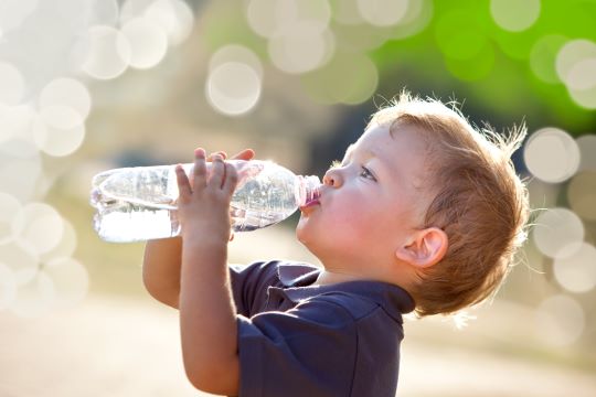 child playing in sprinkler