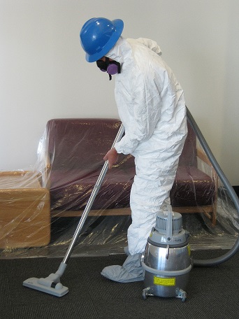 worker in hazmat suit using a hepa vacuum