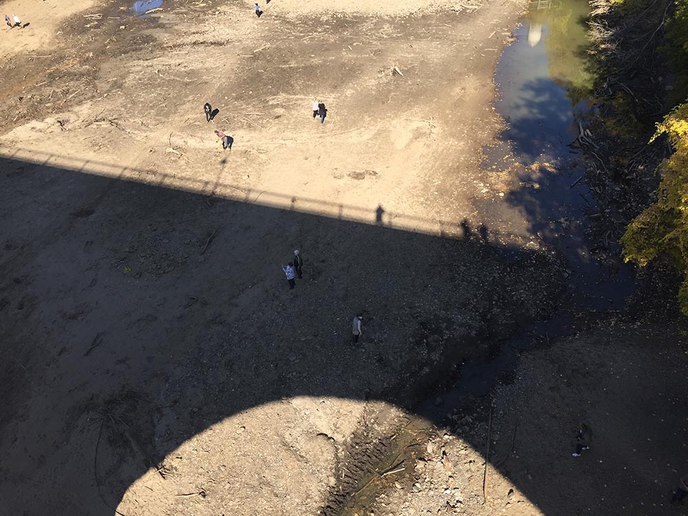 People on the riverbed below the Stone Arch Bridge.