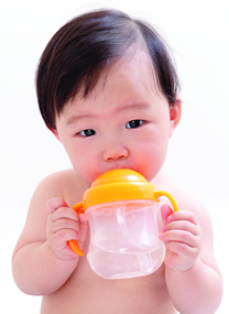 Baby drinking water from a sippy cup.