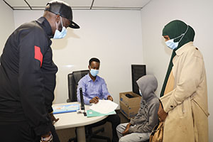 A picture containing four people in a room wearing masks