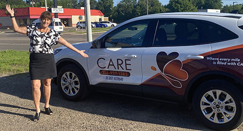 Care staff member stands next to new CARE vehicle