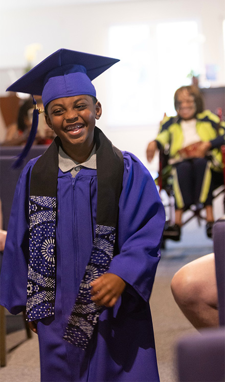 Jasir in cap and gown becomes the first graduate of Morning Glory Montessori
