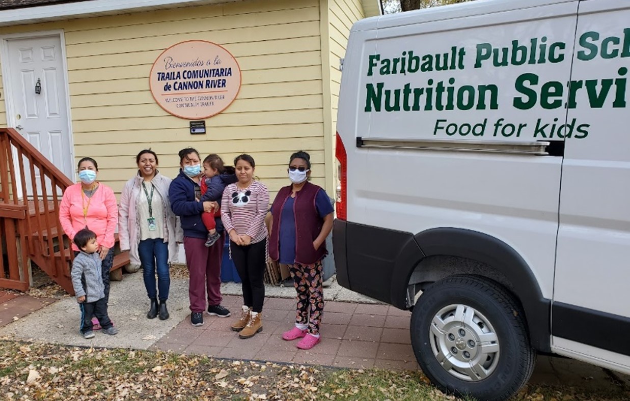 People stand next to a truck that says 'Faribault Public Schools Nutrition Services'