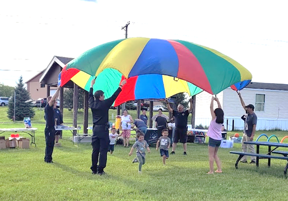 Children run under a multicolored parachute