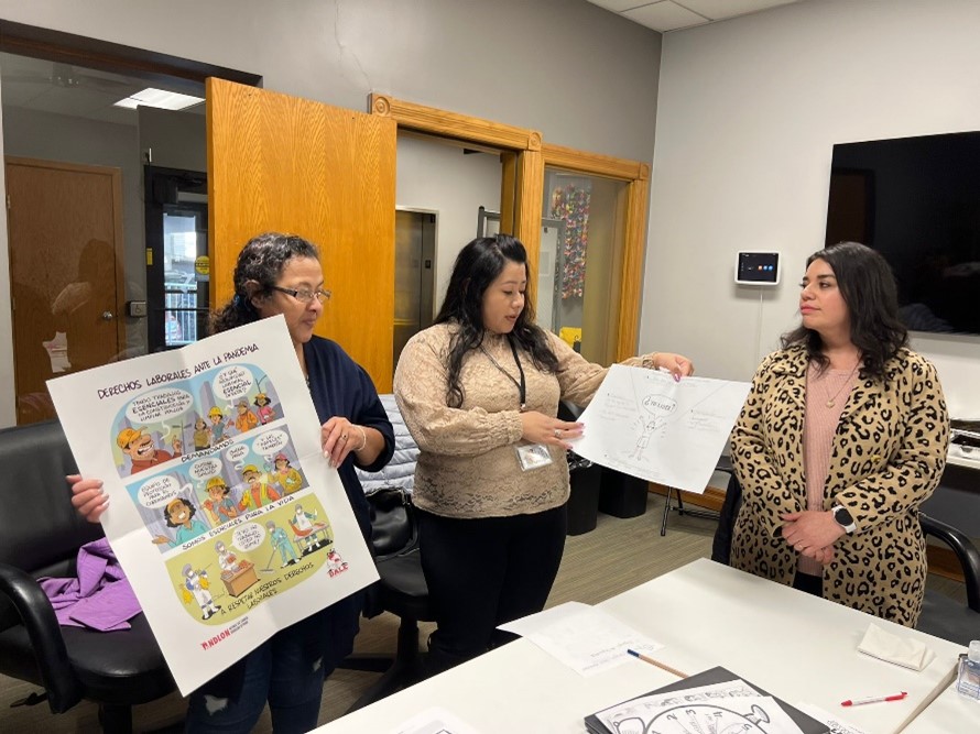 Three promotoras de salud holding health promotion signage