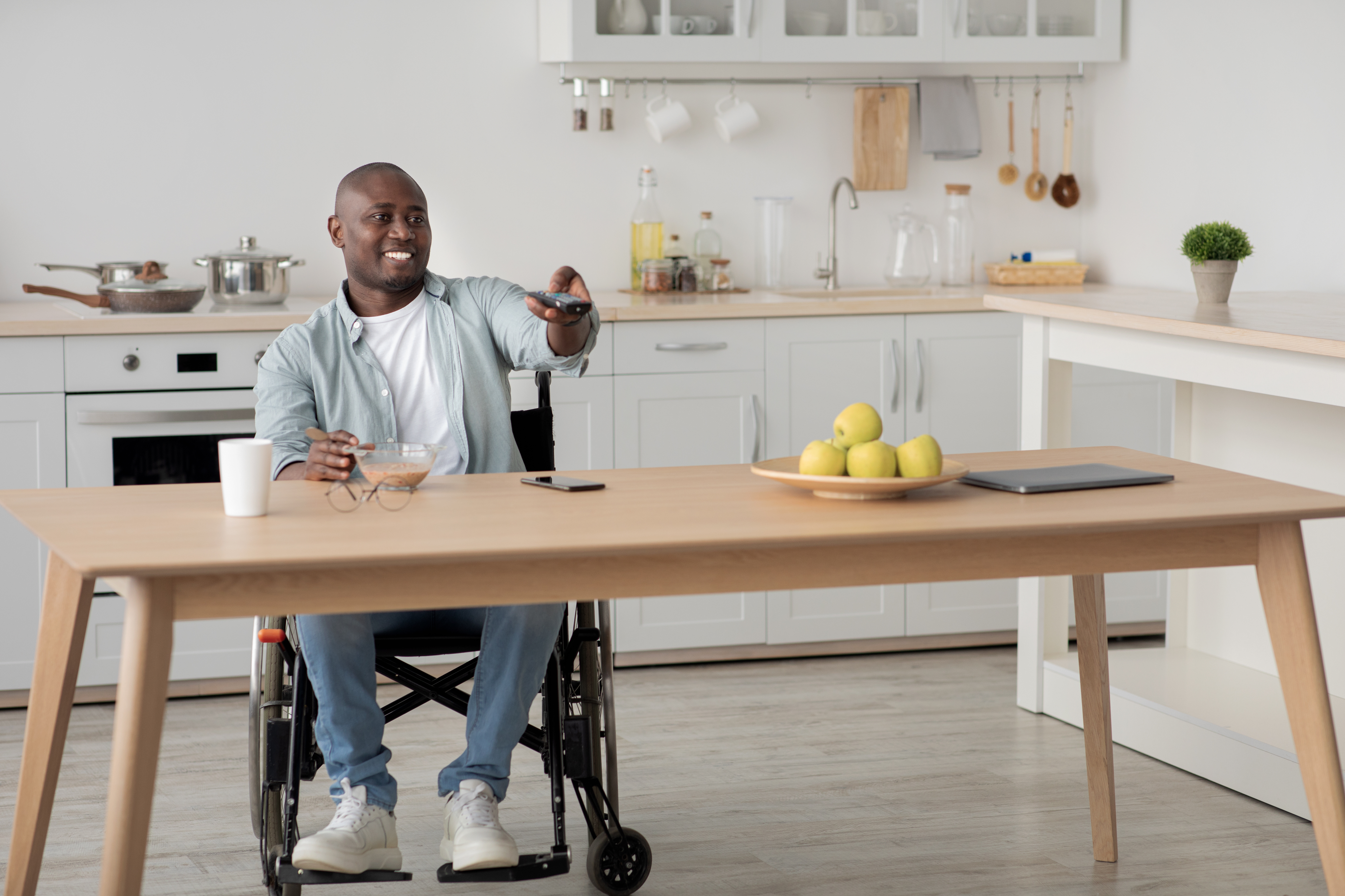Man using wheelchair, with remote control, smiling