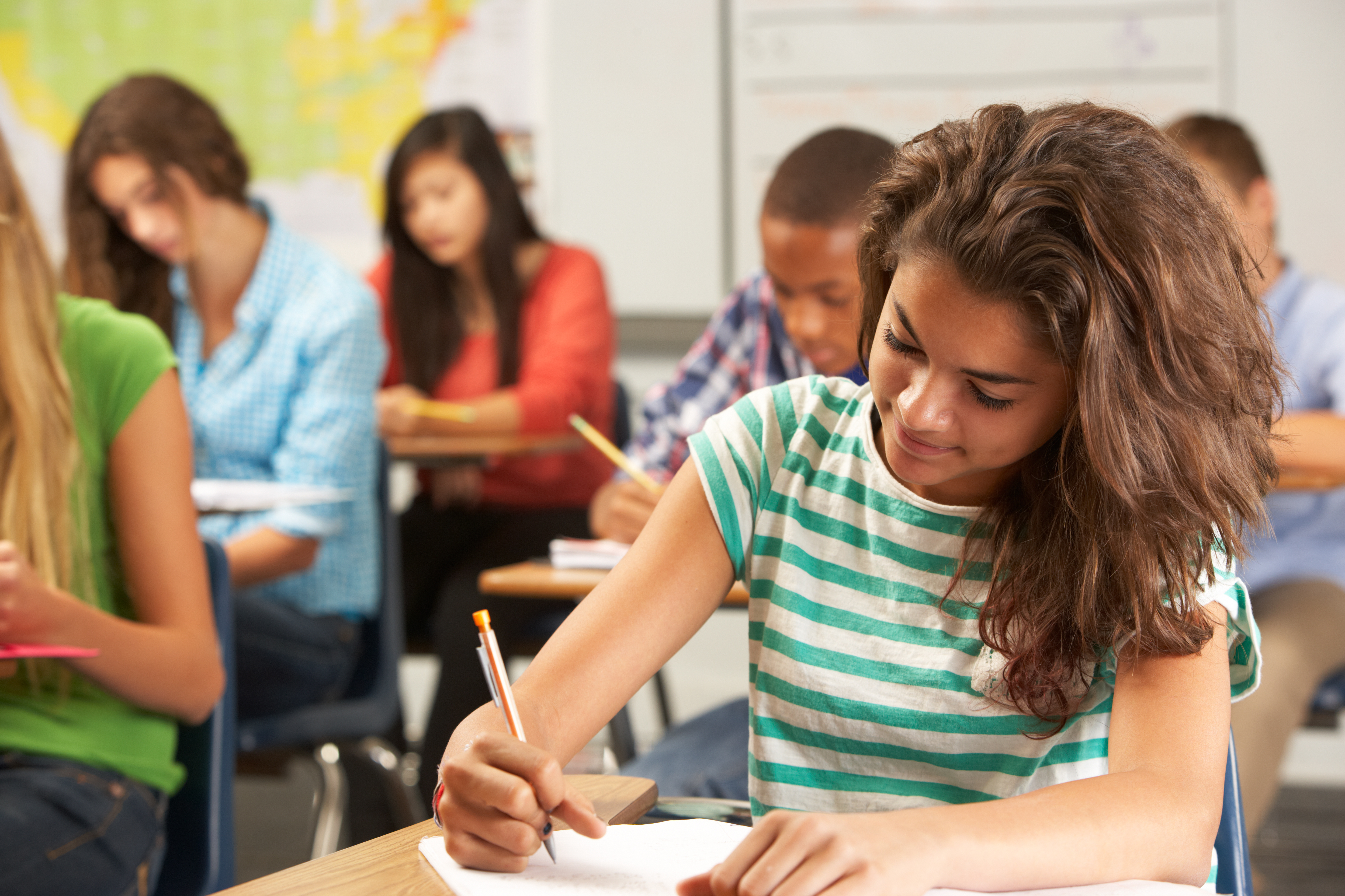 Female-presenting student writing at desk