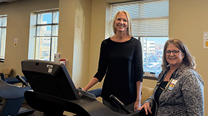 two women stand near a treadmill