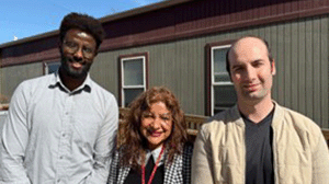 three community health workers stand outside the clinic