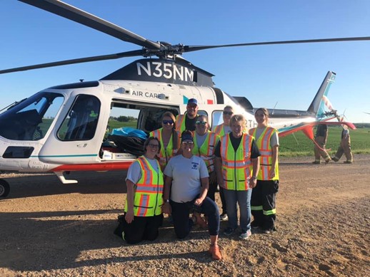healthcare workers in safety vests standing next to a helicopter