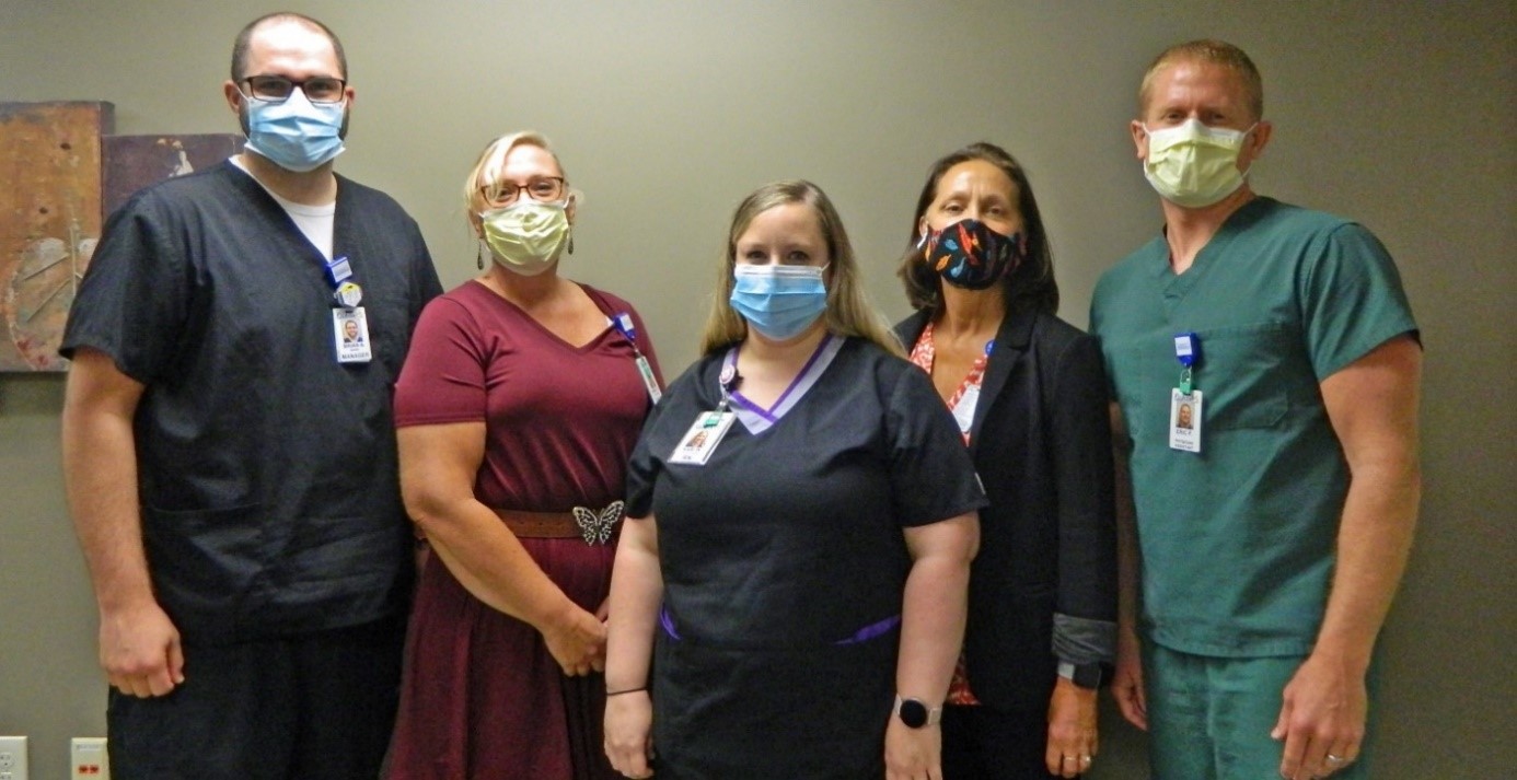 five healthcare workers standing next to each other with masks on