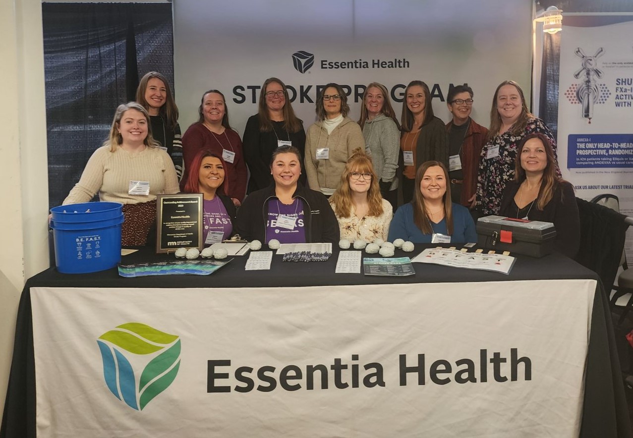 14 women sit behind a booth with an Essentia Health tablecloth.