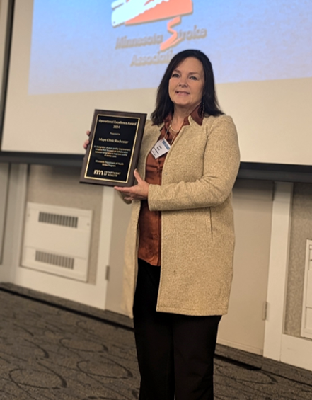 a woman holds an award at the minnesota stroke conference