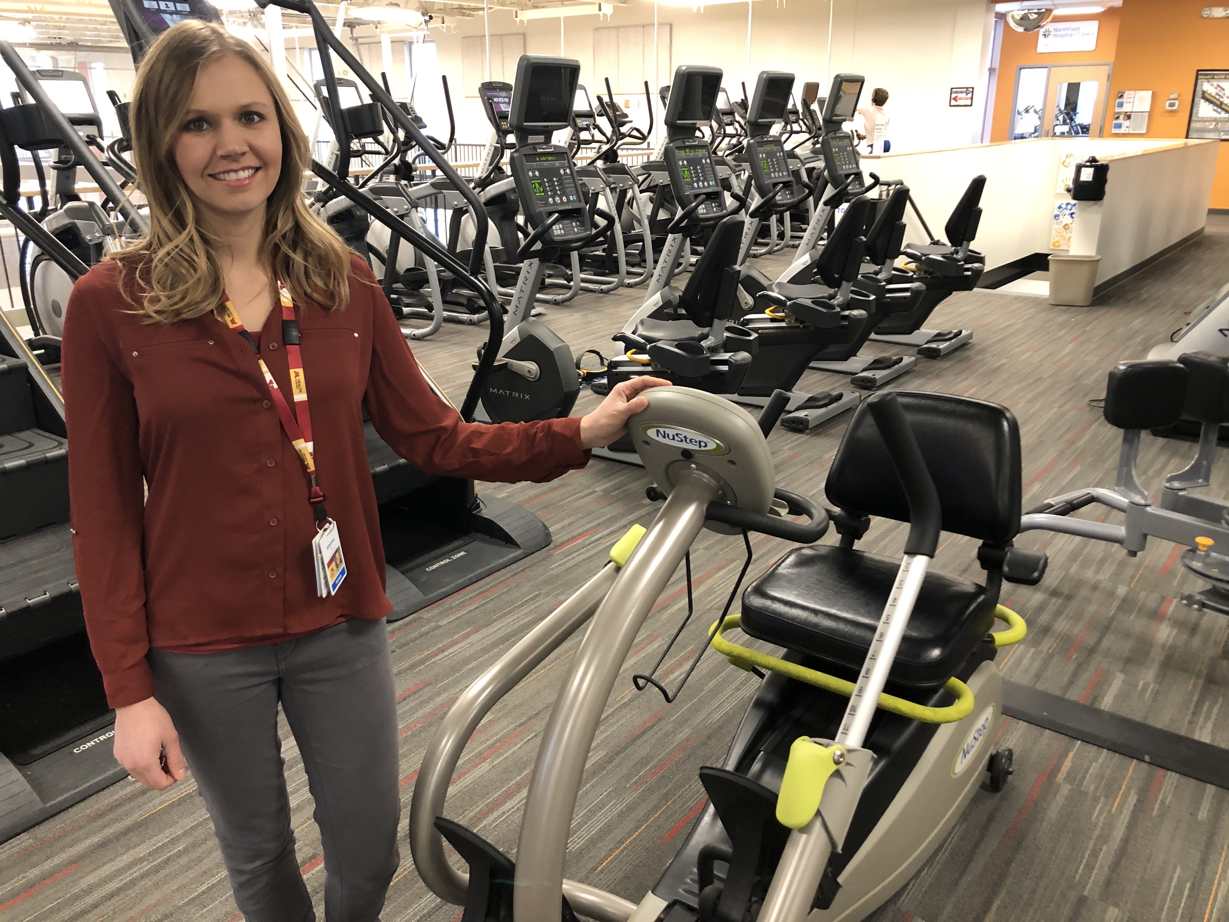 Whitney Quast standing next to a bike in a gym