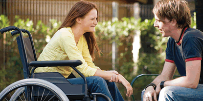Young woman in a wheelchair talking to a young man
