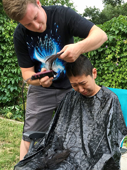Lily's partner shaving her head while she cries