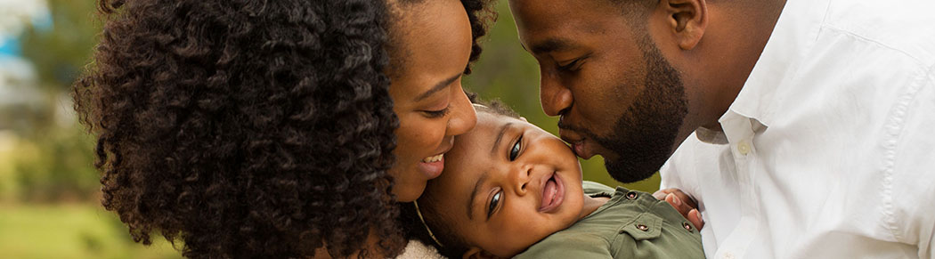 parents holding and kissing happy child