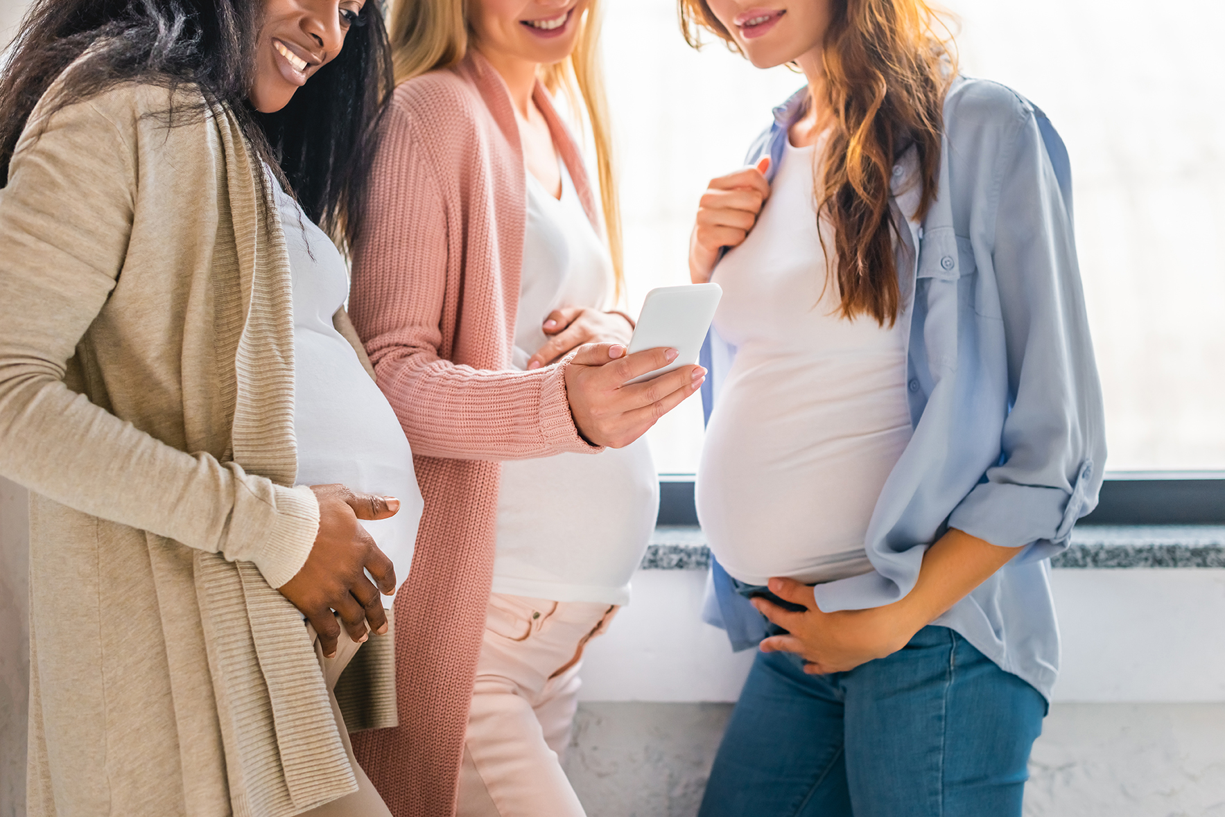 Pregnant women talking looking at a phone.