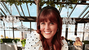 A woman with red hair and bangs wearing a white dress with polka dots